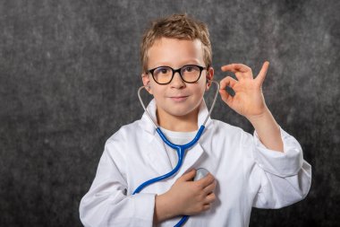 Yakışıklı çocuk tıp üniforması giyiyor doktorculuk oynuyor, portre yapıyor.