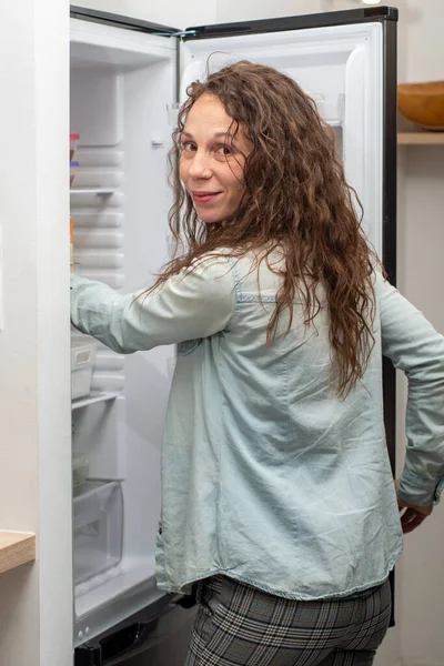 Modern attractive woman with long hair in the kitchen opening  f — Stockfoto