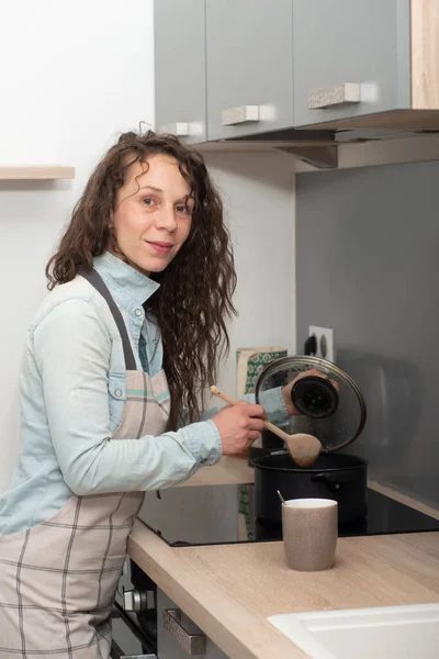 Mujer joven con el pelo largo está en la cocina — Foto de Stock