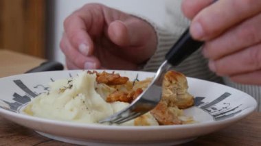 Elinde çatal, elinde patates püresi ve tabakta et olan bir adama yakın dur. 
