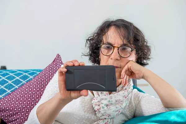 Cheerful Brunette Senior Woman Using Smartphone While Sitting Sofa — Stock Photo, Image