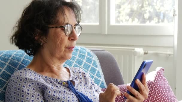 Χαρούμενη Μελαχρινή Ηλικιωμένη Γυναίκα Που Χρησιμοποιεί Smartphone Ενώ Κάθεται Στον — Αρχείο Βίντεο