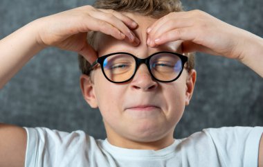 Gözlüklü bir çocuğun başı ağrıyor.