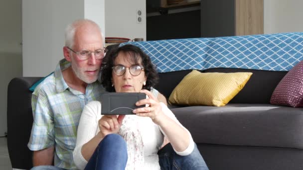 Ώριμο Ελκυστικό Ζευγάρι Κάθεται Στον Καναπέ Χρησιμοποιώντας Smartphone — Αρχείο Βίντεο