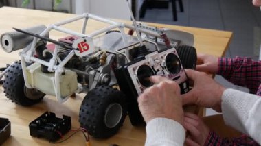 Büyükbaba ve oğul uzaktan kumandalı araba tamir ediyorlar. 