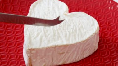 Fransız Neufchatel peynirini kırmızı tabakta kesmek