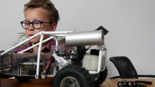 小さな男の子が家でモデル無線制御車を修理し — ストック動画