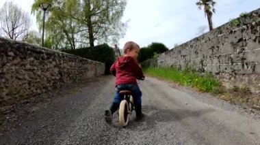 Küçük çocuğun arka manzarası dengeli bisiklete binmesi, yavaş çekim