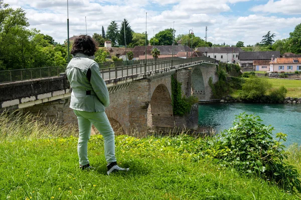 a woman looking Ancient bridge over the river Gave d`Oloron at town of Navarrenx, France.