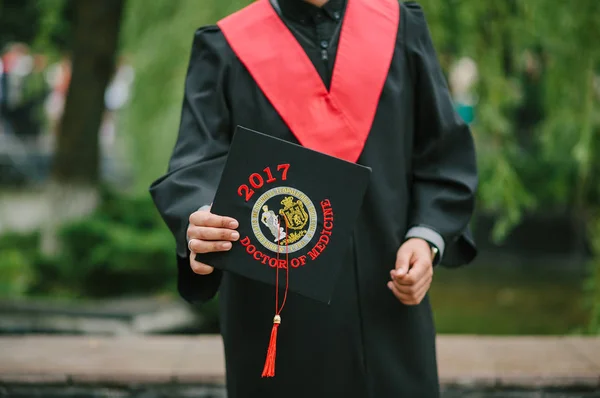 A graduate of a medical university holds a hat in his hand