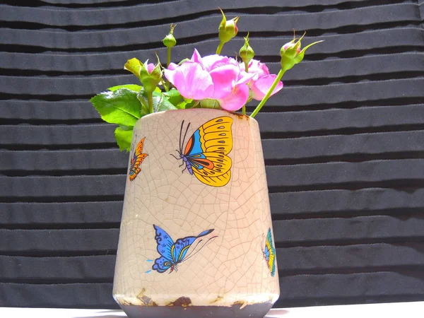 beautiful homemade roses in an old vase decorated with different butterflies.