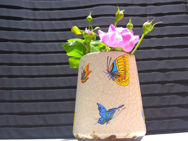 beautiful homemade roses in an old vase decorated with different butterflies.