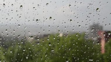 Bahar zamanı pencere camına yağmur damlaları düşer.