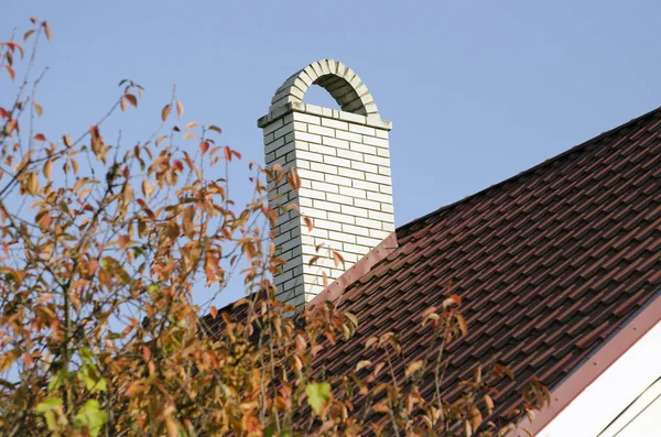 Komin z białej cegły na brązowym dachu domu — Zdjęcie stockowe