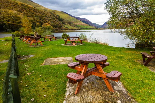 Picnic tables by lake — Stock Photo, Image