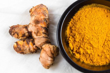 Zerdeçal kök beyaz bez arka plan üzerinde toz kase ile