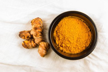 Zerdeçal kök beyaz bez arka plan üzerinde toz kase ile