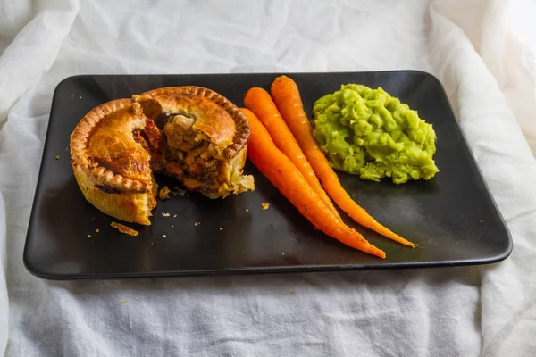 Torta salgada servida com cenouras vitrificadas e ervilhas . — Fotografia de Stock