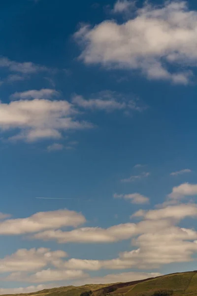 Mraky na vodítkové obloze, zelený kopec dole. — Stock fotografie