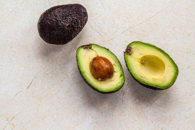 İki avokado armudu, bir kesik, mermer arka plan..