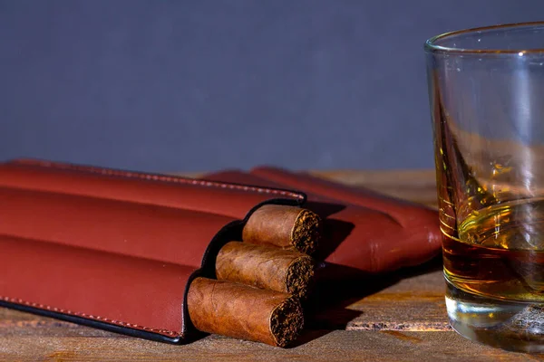 cigars in a case and a glass of whiskey