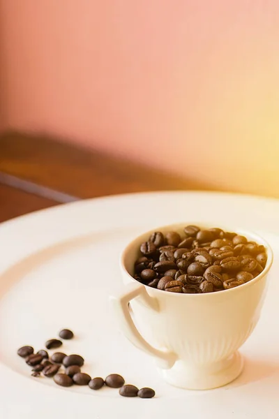 Granos de café en taza en plato blanco con efecto de luz cálida, estilo vintage . — Foto de Stock