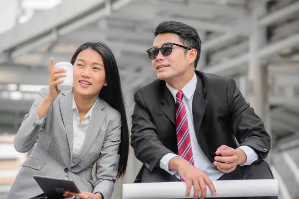 Two happy business people sitting and talking outdoor.