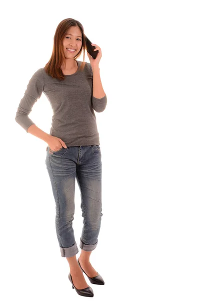 Ayakta ve arka plan üzerinde smartphone kullanarak rahat gülümseyen kadın