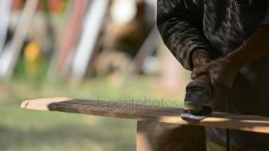 Marangoz bir elektrik süpürgesi ile çalışır ve Ahşap ürünler işler. Ahşap üzerinde elinde el elektrik süpürgesi ile marangoz.