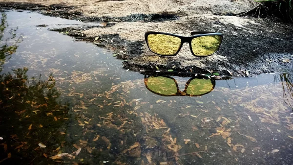 背景の自然に覆われた水面の反射を持つナイトビジョングラス — ストック写真