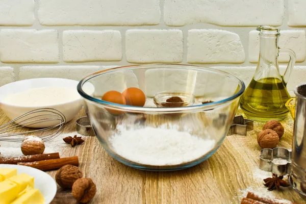 Tools and products for baking homemade gingerbread cookies on a wooden background. The concept of the holiday, celebration and cooking. Eggs, butter, flour, cocoa, nuts, vanillin, anise, cones. — Stock Photo, Image