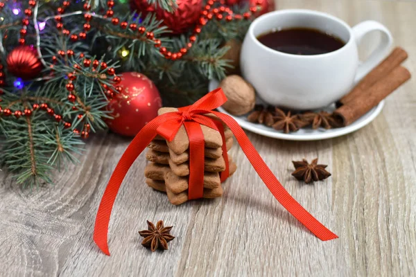 White cup with black tea on the christmas tree phoenias on a wooden table. Red balls. Vanilla, nuts, anise. Spicy cookies. — Stock Photo, Image