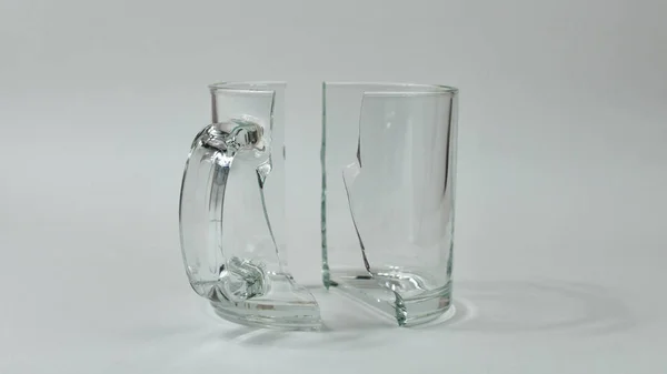 A glass cup broken into two halves on a gray background. Two halves of a broken cup. — 스톡 사진