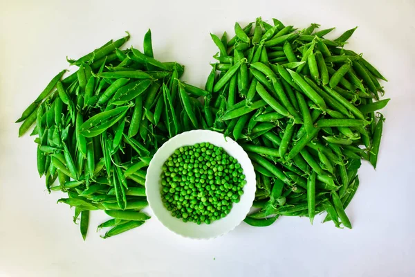 Guisantes verdes en un tazón blanco pelado y en tartas. El concepto de una nutrición adecuada . —  Fotos de Stock