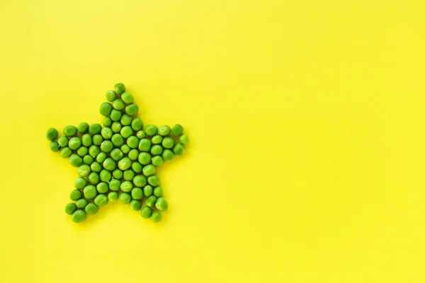 Star laid out of green peas on a yellow background. — Stockfoto