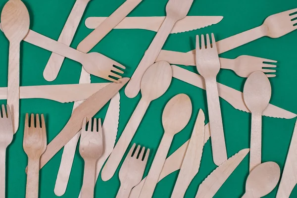 Wooden spoons, forks, knives on a green background. Zero waste concept. — Stockfoto