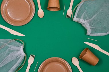 Eco-friendly, disposable, cardboard, paper utensils on a green background. Place for an inscription.