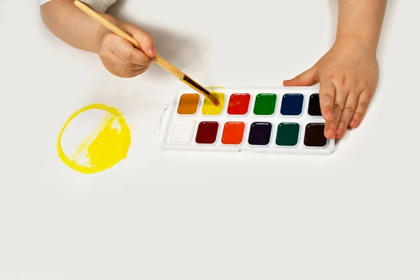 A gyerekkezeket ecsettel és akvarellekkel festik. Gyermeki kreativitás, festészet, korai fejlődés. — Stock Fotó