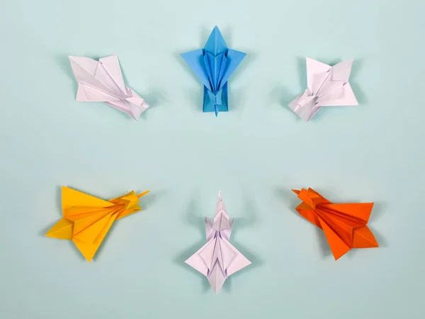 Origami. Paper swans of different colors look in a circle. The concept of unity.