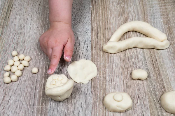 Childs hand sculpts from salt dough, clay, plasticine on a wooden background. Childrens creativity. Manual creativity. Sculpt at home.