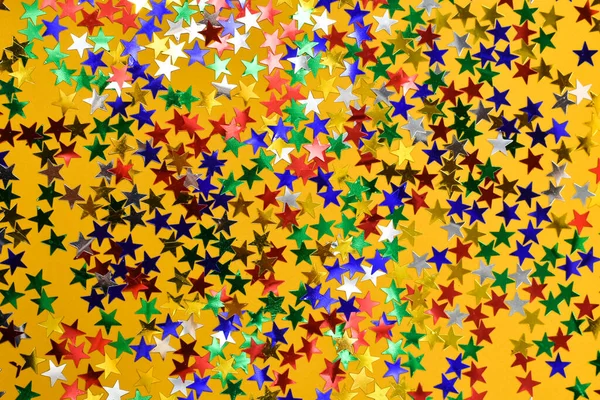 Estrelas brilhantes multicoloridas em um fundo amarelo. Fundo da estrela . — Fotografia de Stock