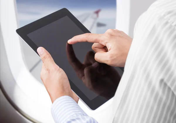 Бизнесмен проверяет фондовый рынок на планшете в самолете — стоковое фото