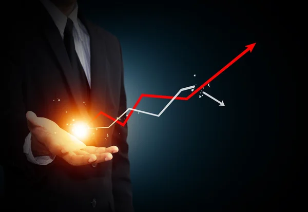 Hand hält einen aufsteigenden Pfeil, der das Wirtschaftswachstum repräsentiert. — Stockbild Hand hält einen aufsteigenden Pfeil, der das Wirtschaftswachstum repräsentiert. — Stockfoto