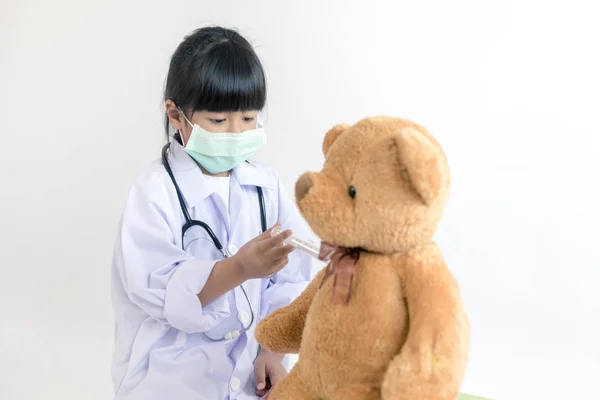 child playing doctor with stethoscope and teddy bear