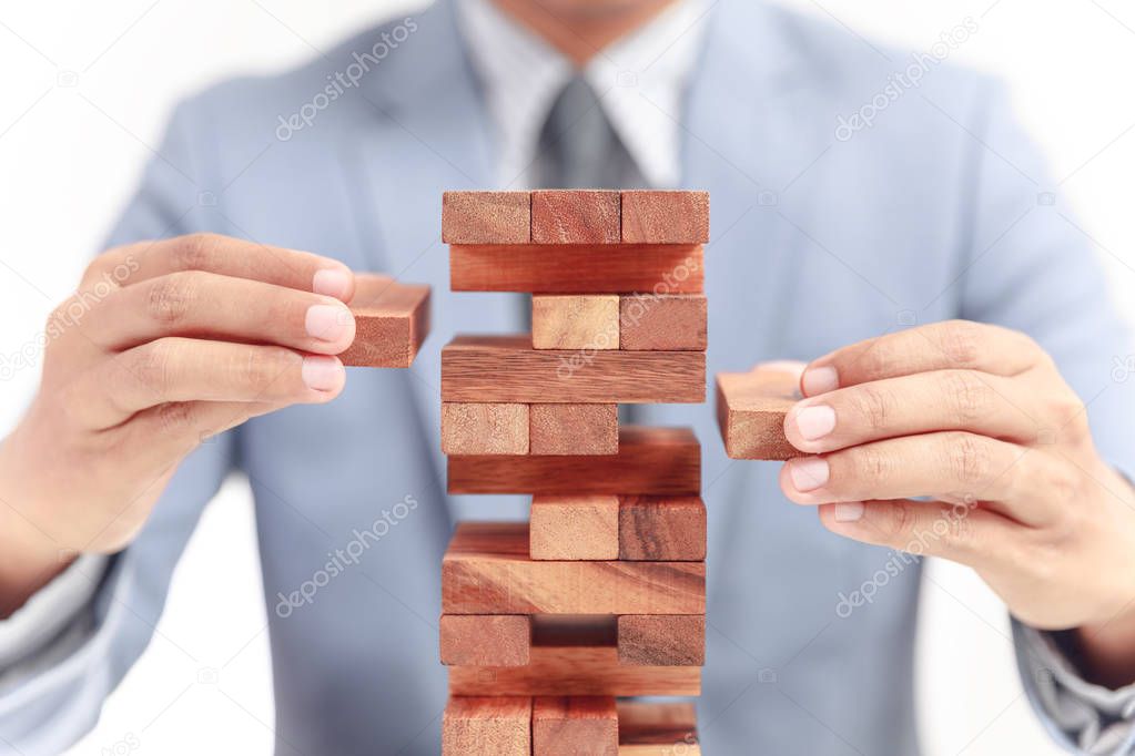 businessman building tower of wooden blocks