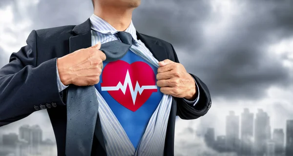 Businessman in superhero costume with heartbeat — Stock Photo, Image