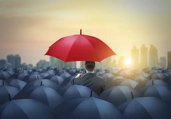 Guarda-chuva vermelho único entre guarda-chuvas pretos com fundo da cidade — Fotografia de Stock