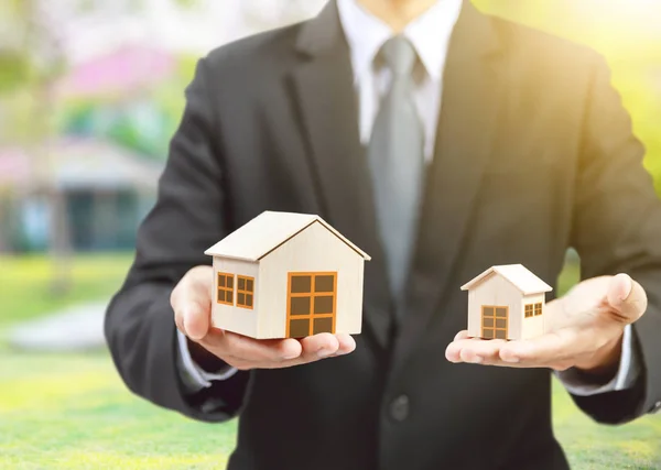 Businessman hold big and small houses on hand — Stock Photo, Image