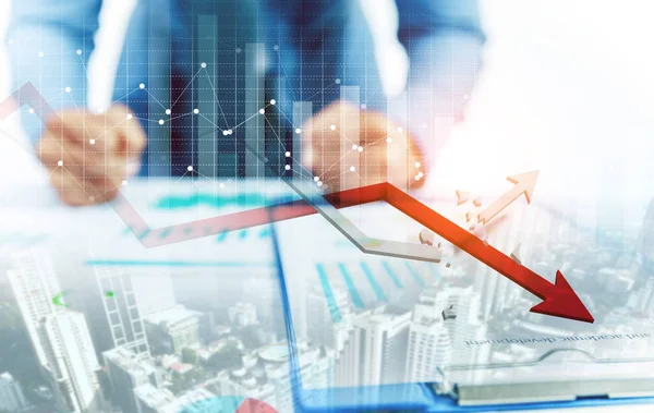Geschäftsmann zeigt auf abnehmendes Diagramm und zunehmendes gebrochenes Diagramm mit Stadthintergrund — Stockfoto