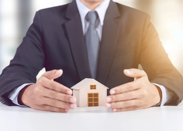 Hombre de negocios cubierta de mano modelo de casa de madera, concepto de seguro — Foto de Stock